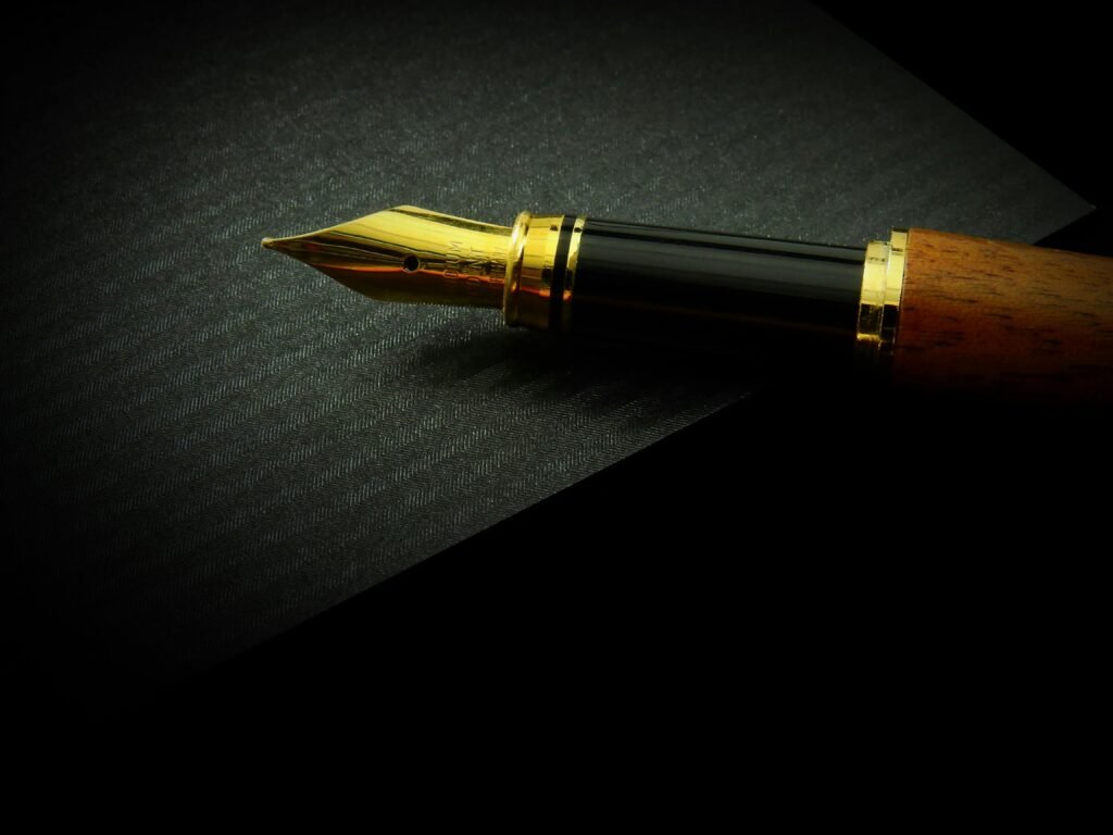 A close-up of a luxurious fountain pen with a golden nib resting on a dark textured writing surface, symbolizing the craft and discipline of writing.