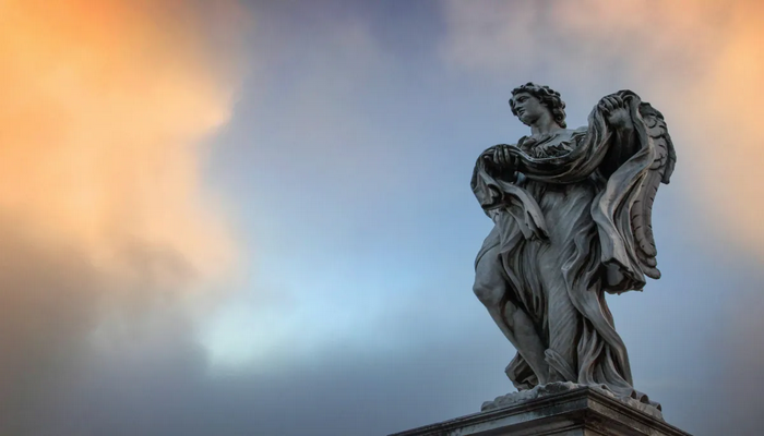 Stone statue of a robed woman, captured against a dramatic sunrise sky with soft orange and blue clouds, symbolizing inspiration and waiting.