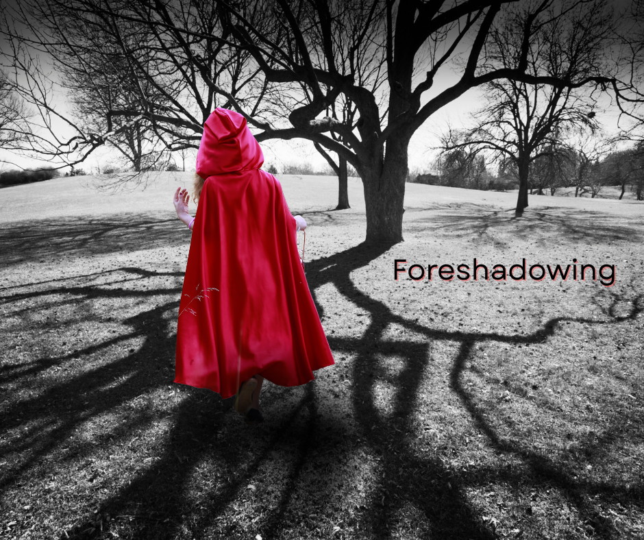 A figure in a bright red cloak walks across a black-and-white field toward a tree whose shadow stretches long across the ground. The word “Foreshadowing” appears in dark red letters to the right.